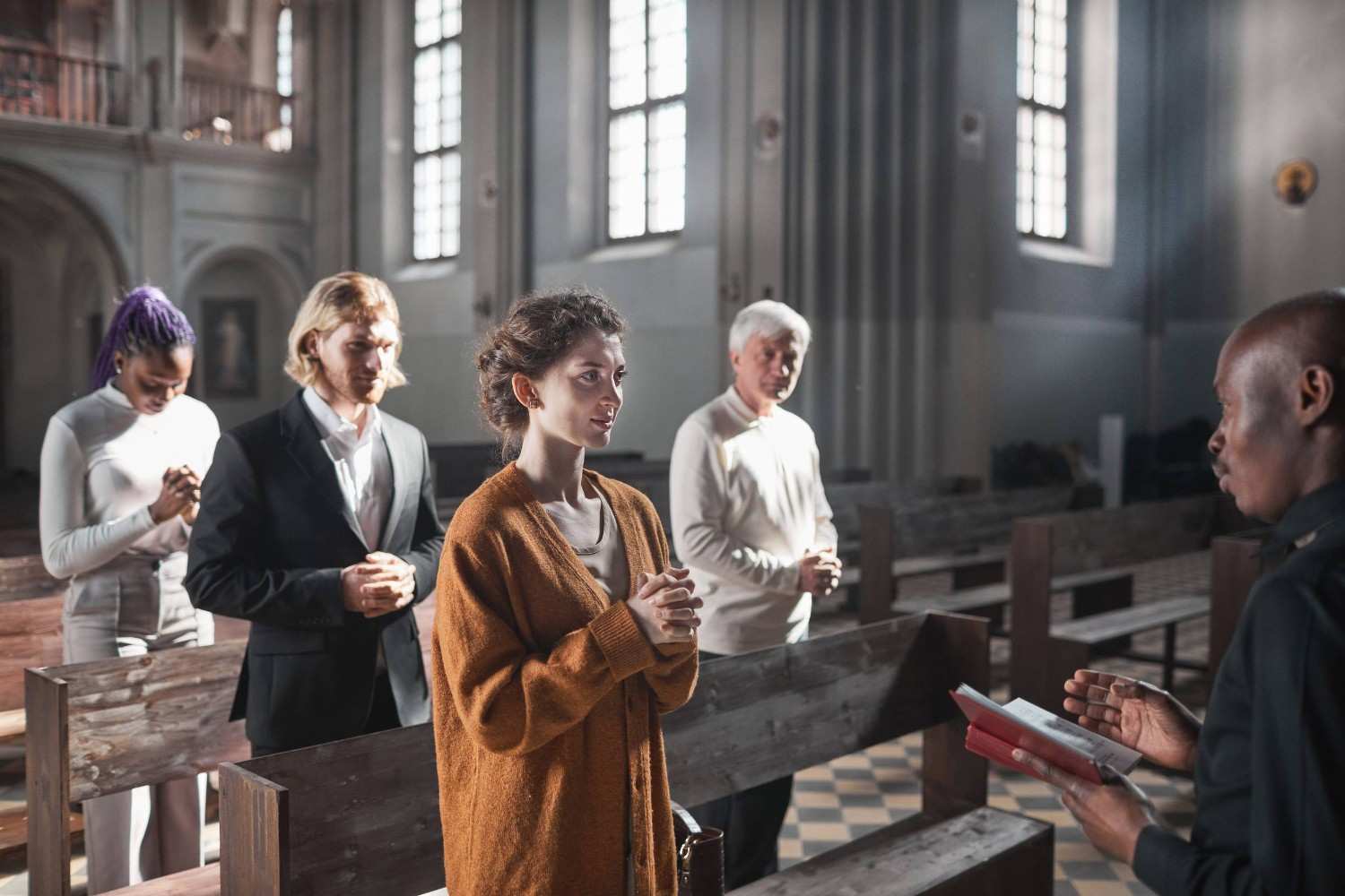 A Group Of People Praying With A Priest