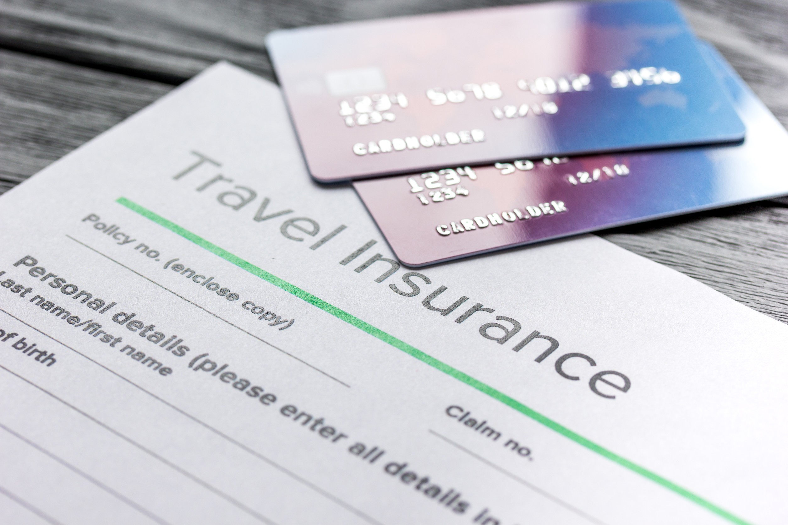 Travel insurance application form with credit cards on gray